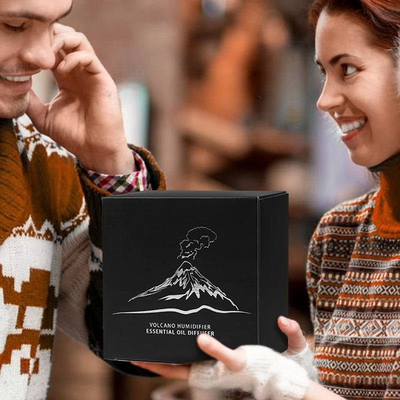 Une femme offre une jolie boite cadeau contenant le diffuseur flamme volcanique d'huiles essentielles à son amoureux