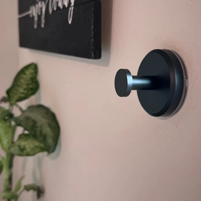 Un beau crochet noir à ventouse est fermement collé sur un mur clair