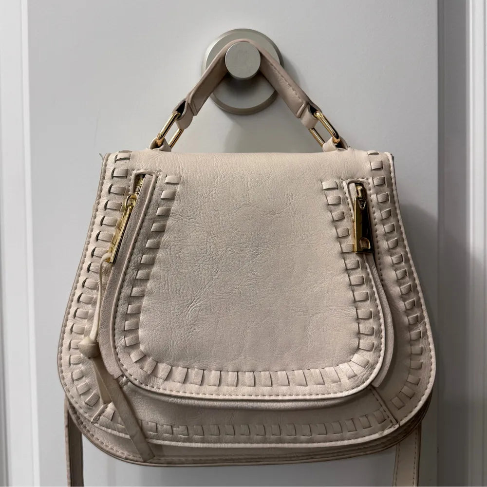 Un crochet design maintient un lourd sac à main en cuir contre un mur clair