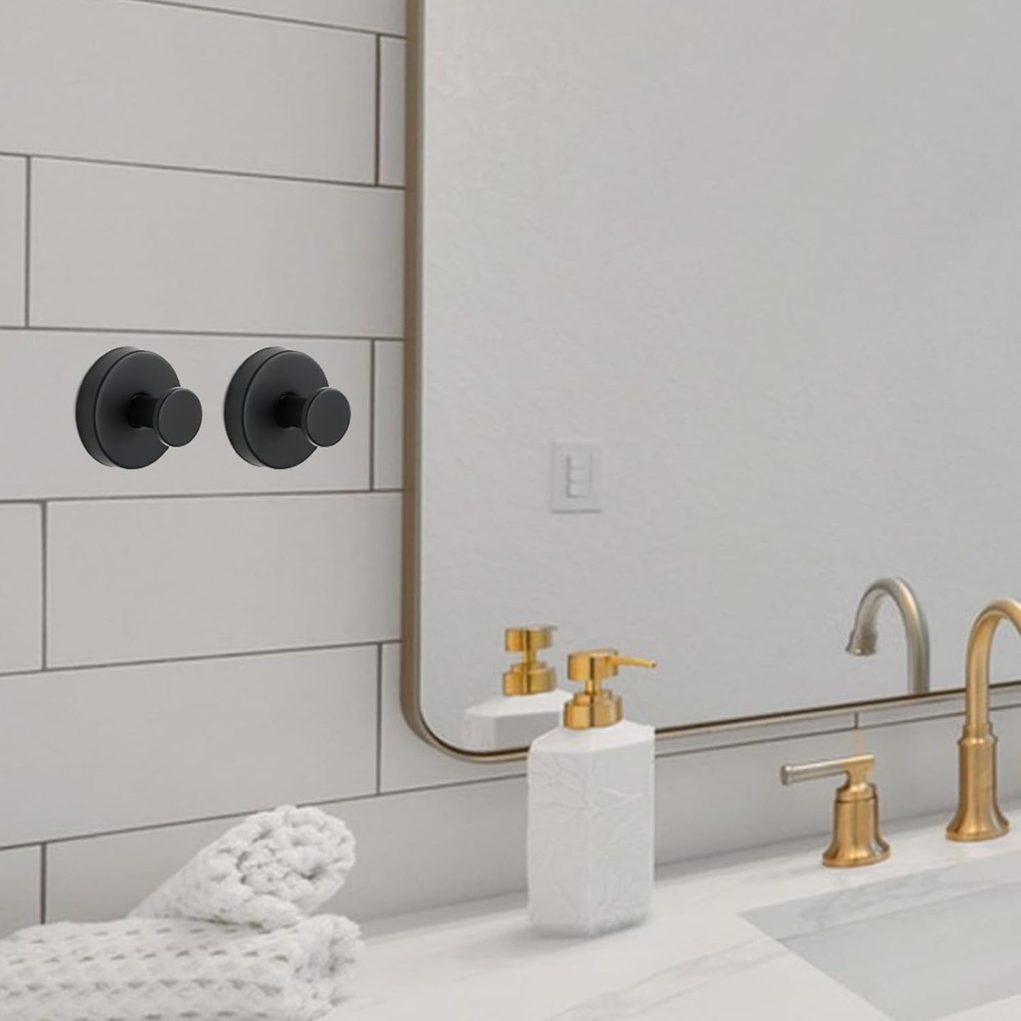 Deux jolis crochets noirs en acier sont fixés contre du carrelage d'une salle de bain