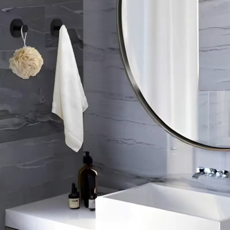 Deux crochets noirs pour salle de bain sont fixés solidement sans clous ni vis contre un mur foncé