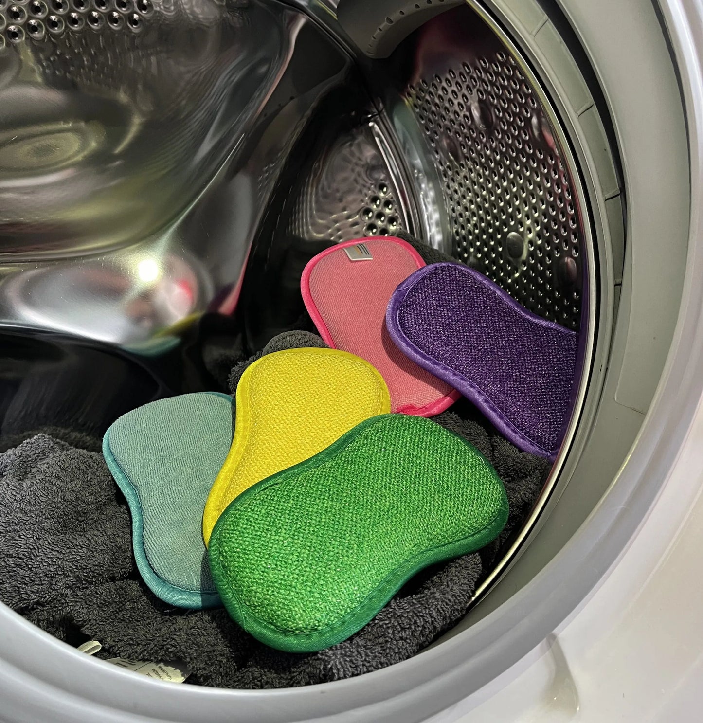Des éponges écologiques réutilisables sont dans une machine à laver prêtes à êtres lavée pour une nouvelle utilisation