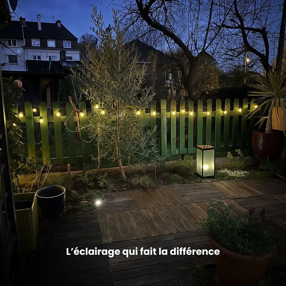 Une guirlande led sur une petite barrière en bois dans un jardin illumine la nuit