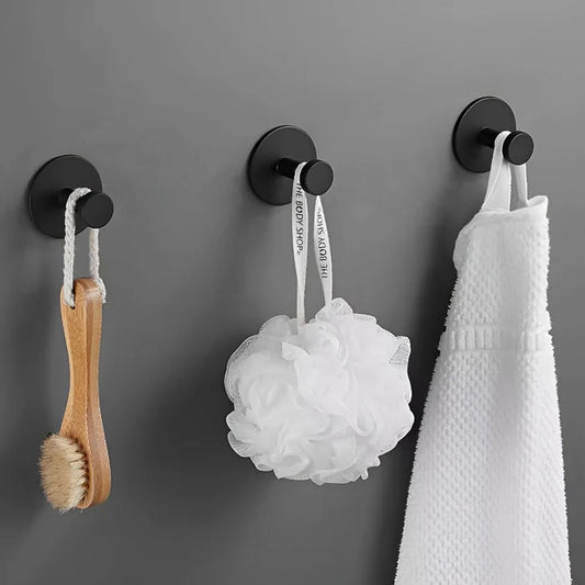 Trois crochets à ventouse noirs sont collés sur un mur gris foncé