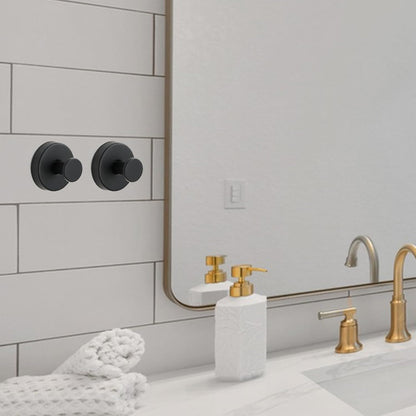 Deux jolis crochets noirs en acier sont fixés contre du carrelage d'une salle de bain