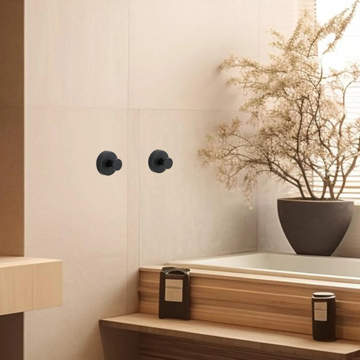 Deux crochets ventouse en acier de couleur noire contre un mur clair