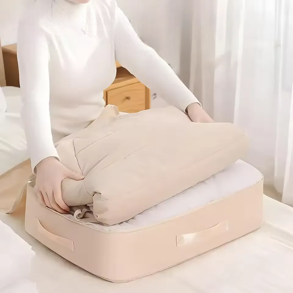 Une femme empile des grosses couvertures dans un sac de compression beige